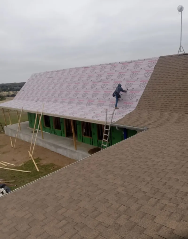 Worker preparing underlayment for a metal roof installation in West Plains